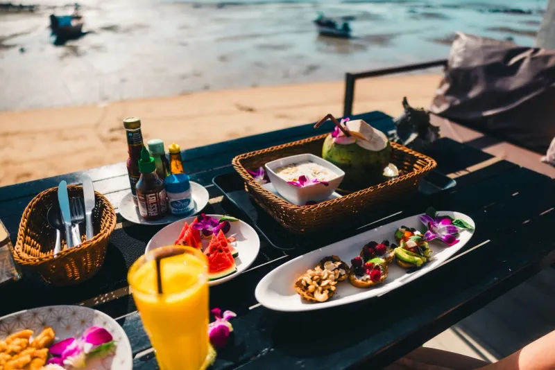 Beachfront dining setup with tropical fruit and drinks at sunset on Koh Samui