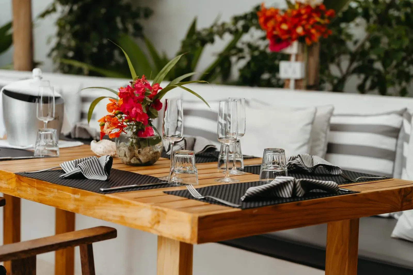 Elegant outdoor dining table with floral centerpiece and glassware at a Koh Samui fine-dining restaurant
