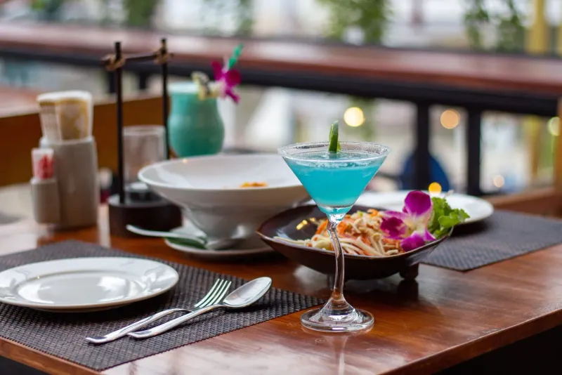 Blue cocktail on a wooden table at a Koh Samui beach bar restaurant