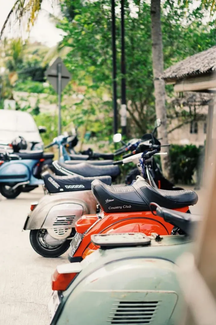Row of scooters parked along a roadside under a sunny Koh Samui sky