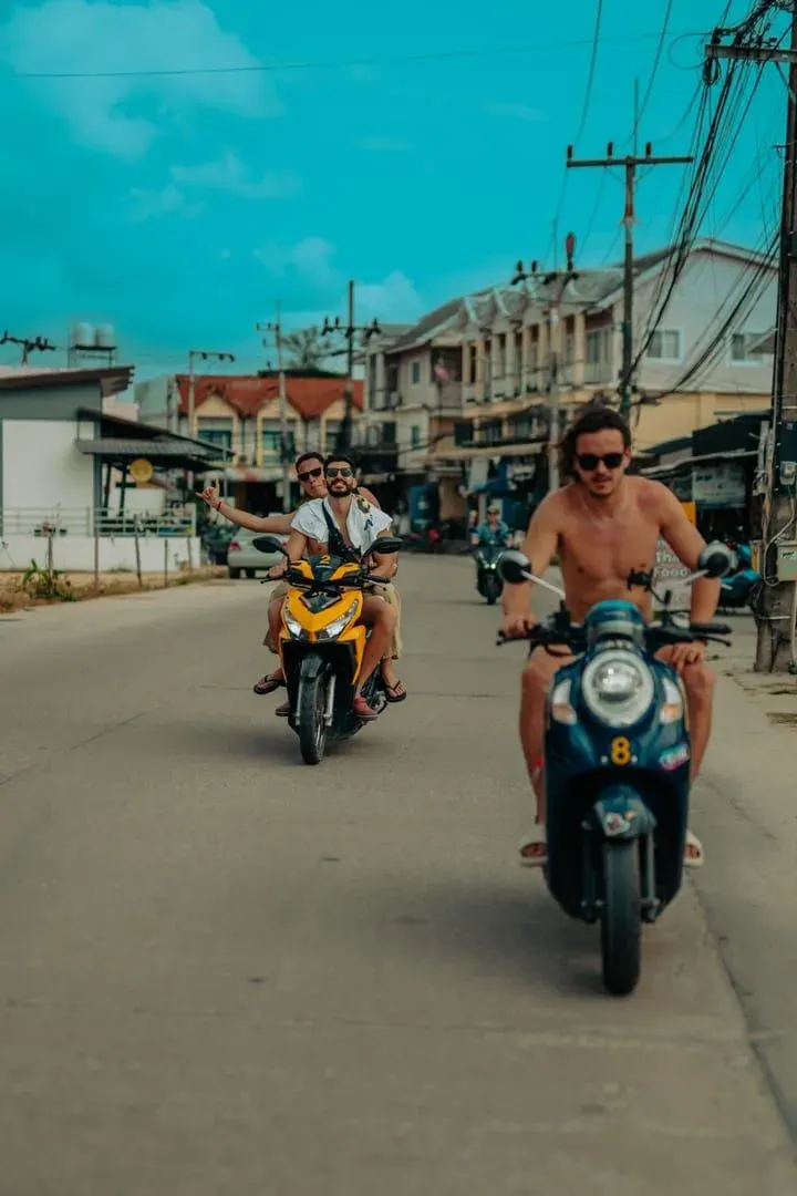 Group of friends riding rental scooters together through an island town