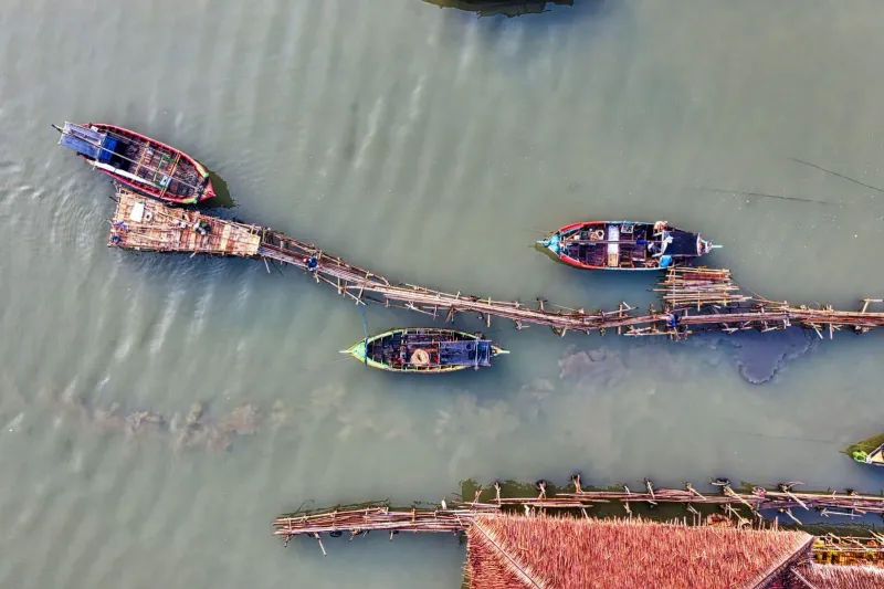 Aerial view of traditional fishing boats docked at a wooden pier on the south coast