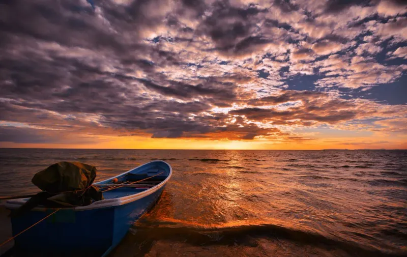 Boat silhouetted against a colorful reflection at sunset near Koh Samui