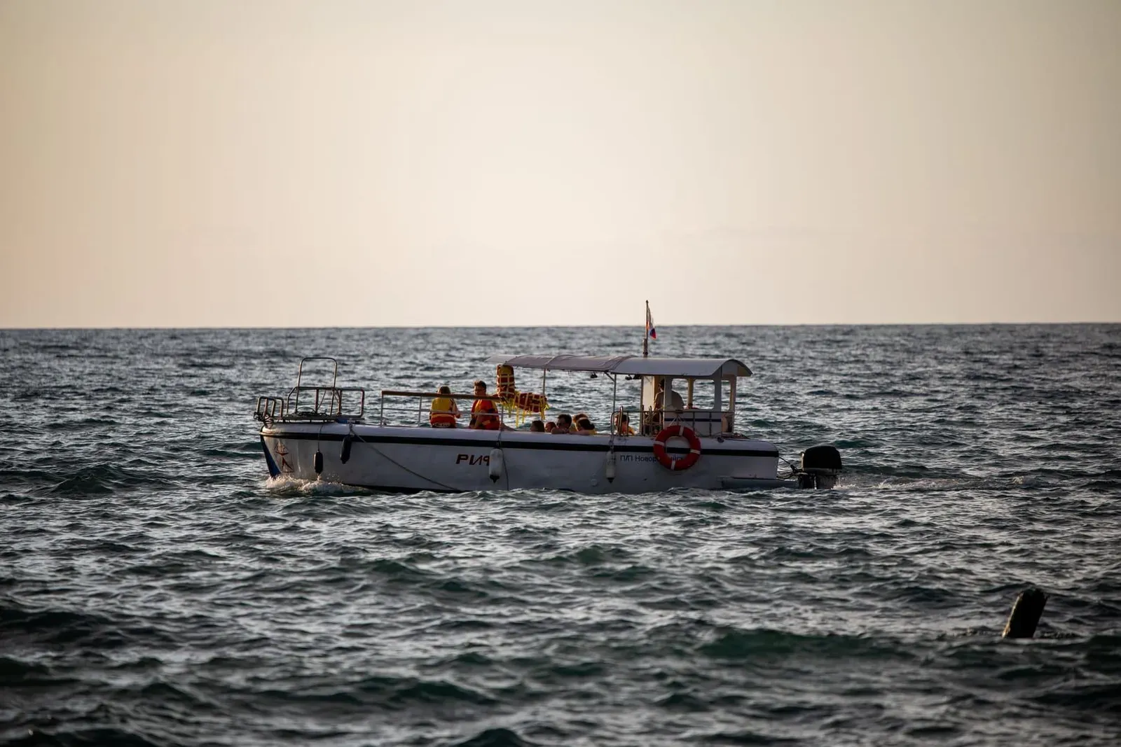 Passengers in life vests riding a boat across calm water at sunset near Koh Samui