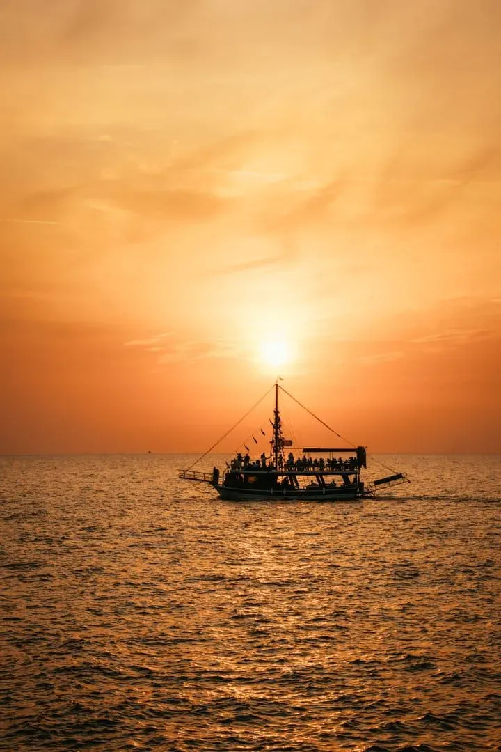Passenger boat sailing at sunset with guests aboard, typical of a shared sunset cruise