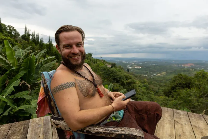 Tattooed traveler relaxes on a terrace overlooking a green forest landscape near Koh Samui