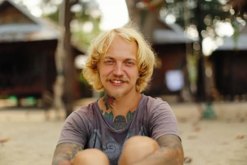 Man with tattoos smiles outdoors in a relaxed portrait after healed studio tattoo work