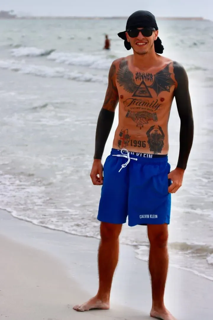 Tattooed man enjoys a sunny day at a beach with healed tattoo work on display