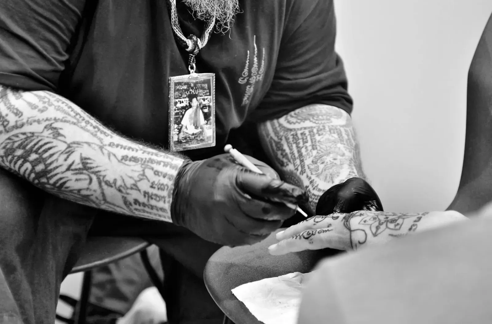 Tattoo artist's gloved hands guide a machine needle across a client's skin during a studio tattoo session