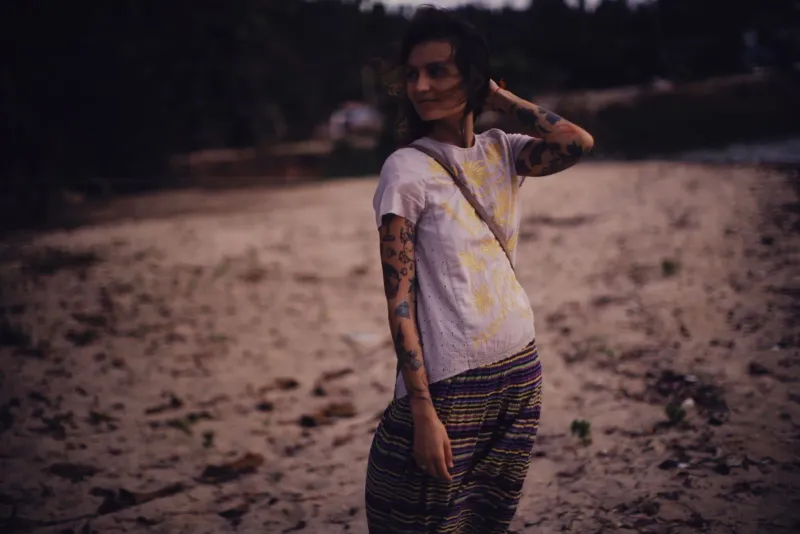 Tattooed woman enjoys a breezy evening on a Thai beach after her tattoo has healed