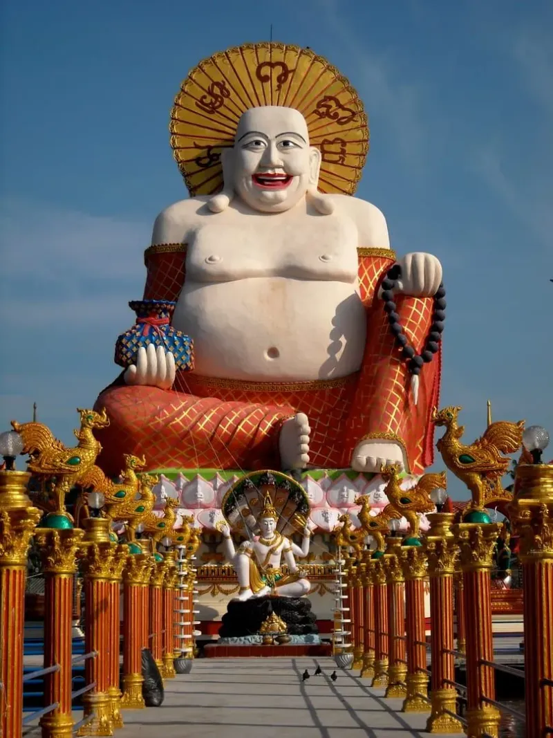 Statua del Buddha tra gli edifici del tempio sul lago di Wat Plai Laem vicino a Bophut, Koh Samui, un esempio di sito misto Theravada e Mahayana