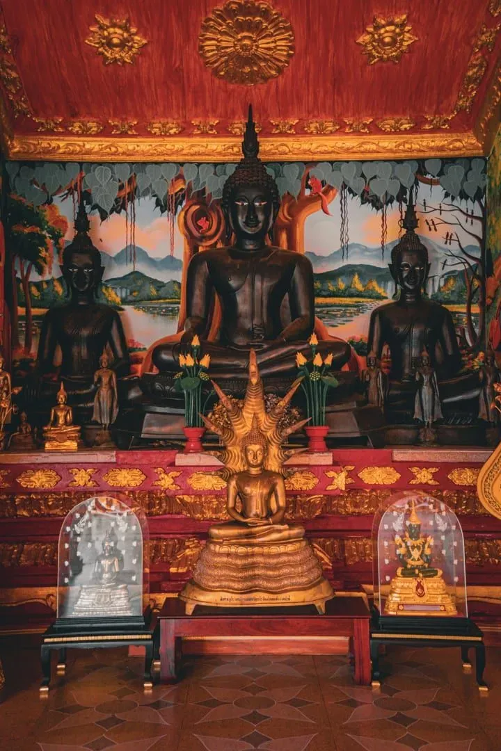 Seated Buddha statues arranged inside a Southeast Asian Buddhist temple hall
