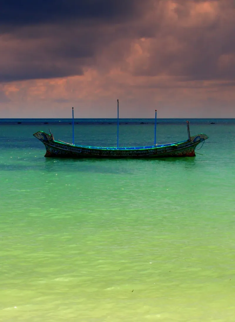 Traditional longtail boat anchored in turquoise water off Koh Samui at dusk