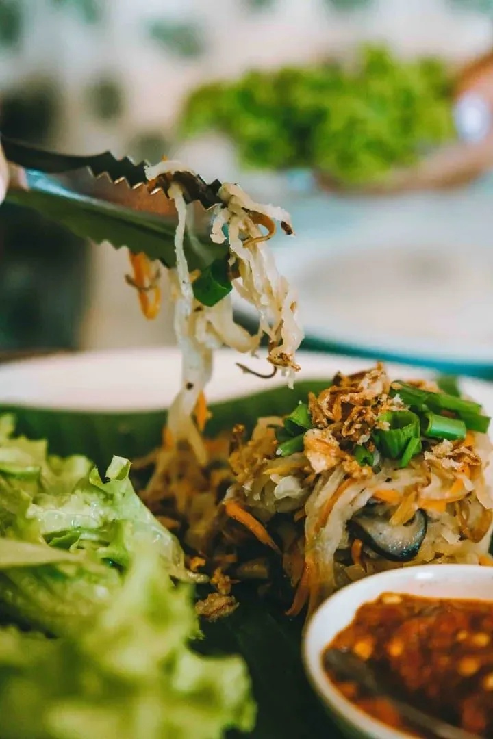 Plate of Thai-style noodles and greens served with a fork