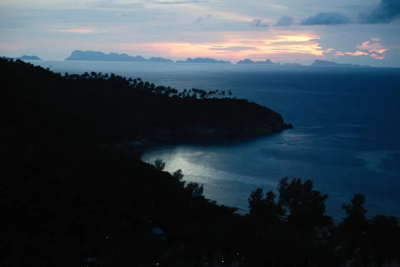 Silhouetted coastline and distant islands at sunset viewed from a Koh Samui hilltop