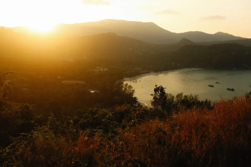 Golden sunset over a tranquil bay and lush hills typical of Koh Samui viewpoint hikes