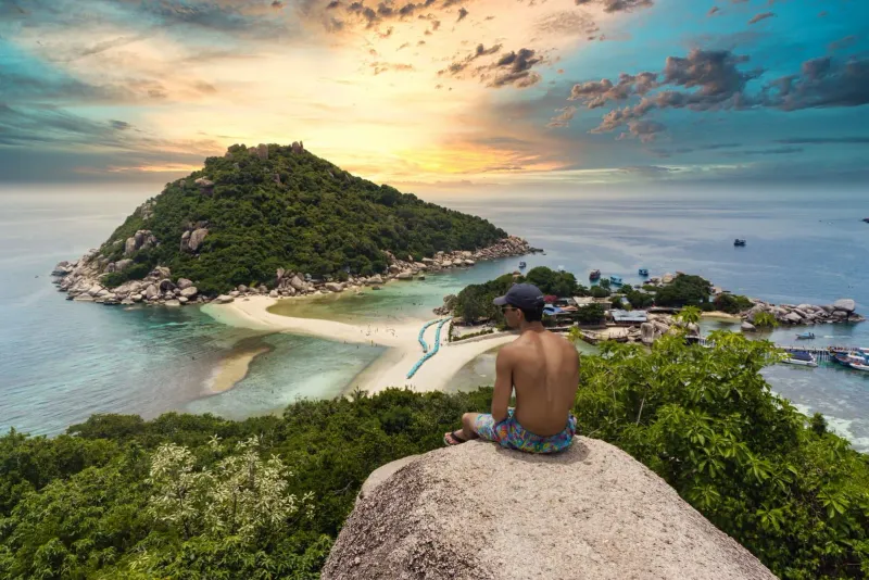 Visitor watching a free sunset from a rocky outcrop on Koh Samui