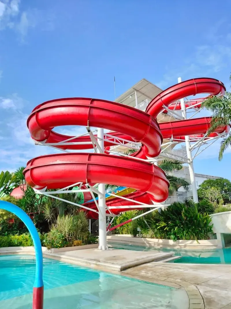 Red water slide at a tropical waterpark comparable to Koh Samui's water park options