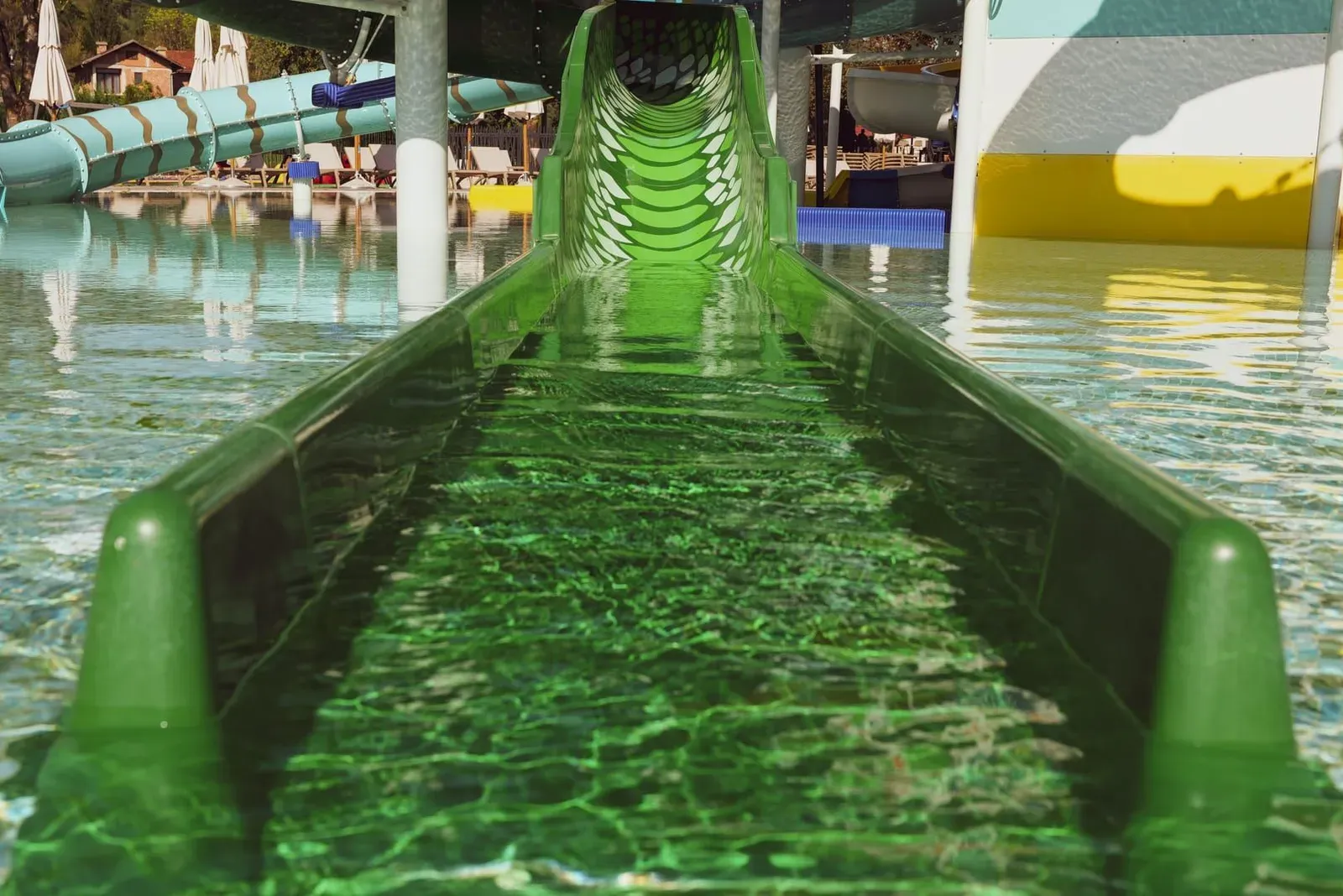 Green water slide at a tropical aquapark, similar in scale to Koh Samui's smaller Coco Splash park