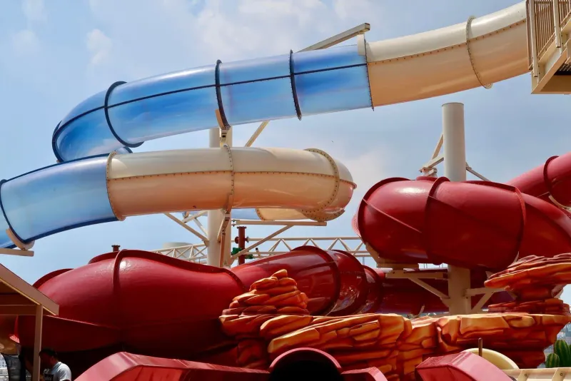 Red and blue water slides under a clear sky at an outdoor water park