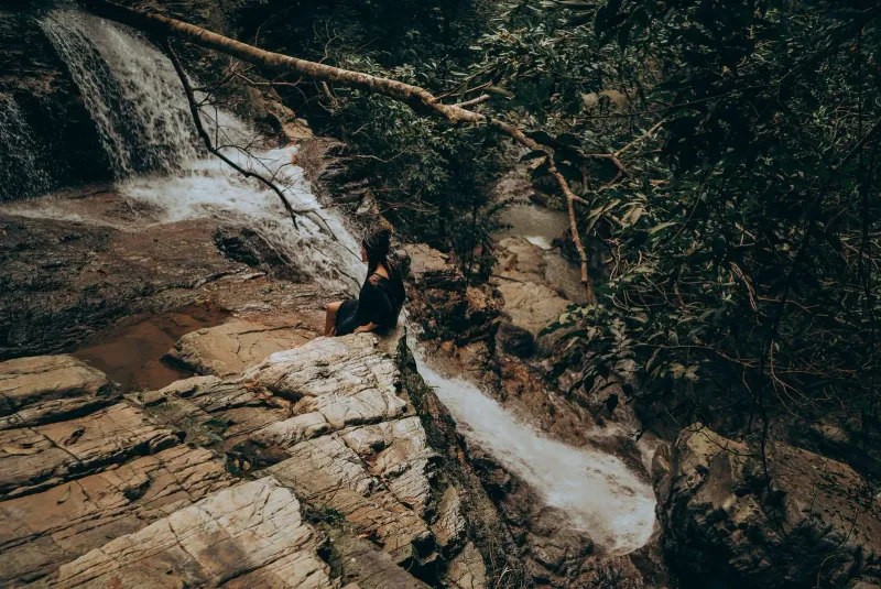 Hiker sitting beside a forest stream on a Koh Samui waterfall hiking trail