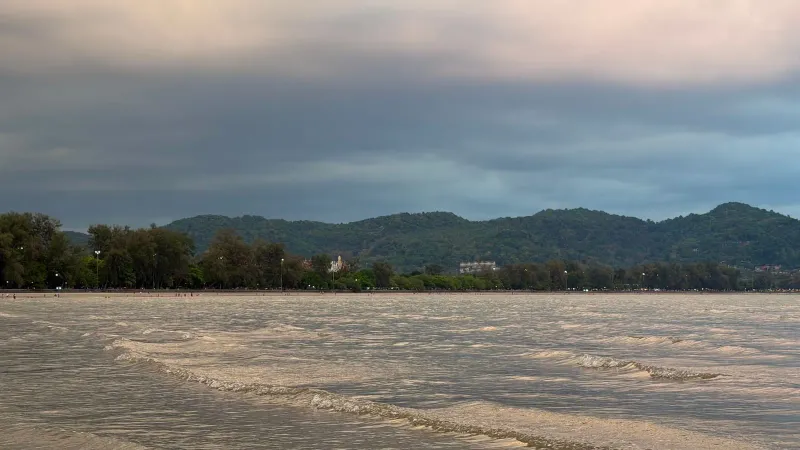 Golden hour light over a calm bay with distant hills illustrating dry-season sea conditions