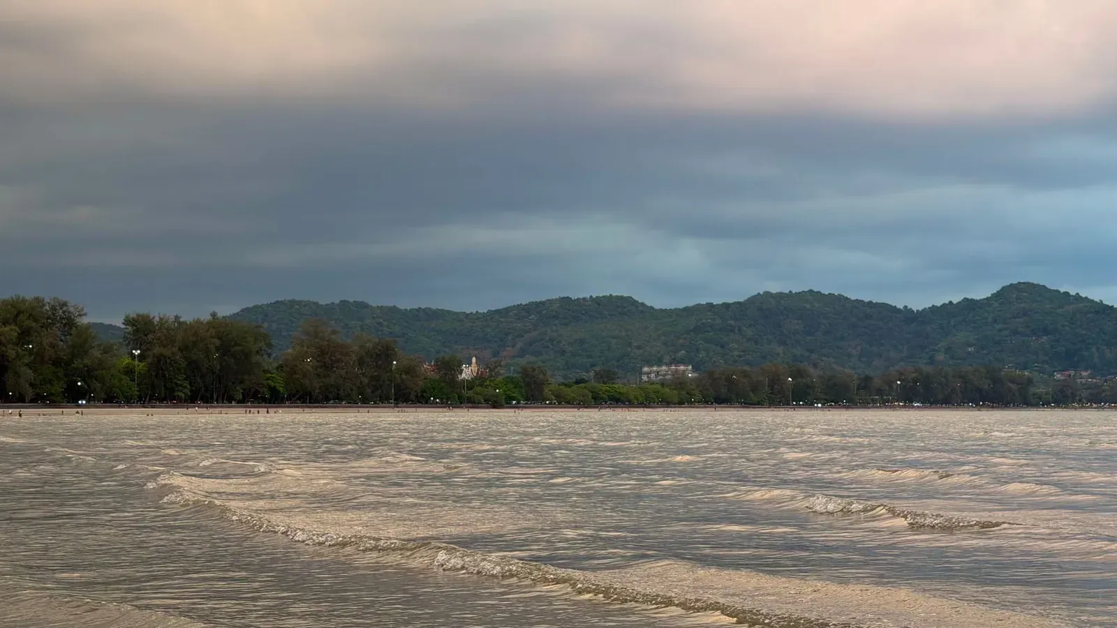 Golden hour light over a calm bay with distant hills, illustrating clear dry-season water conditions
