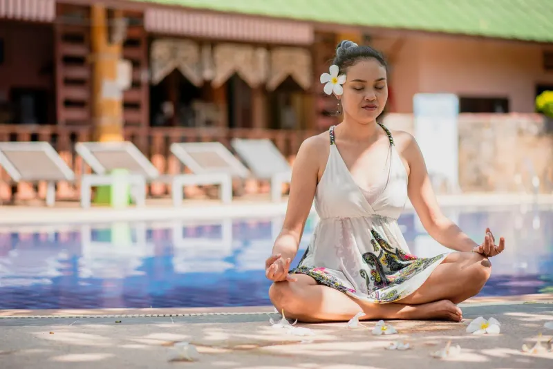 Woman seated in quiet meditation beside a pool in the early morning
