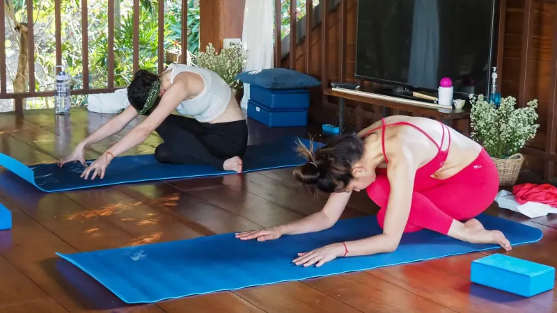 Women stretching indoors during a yoga class at a Koh Samui wellness studio