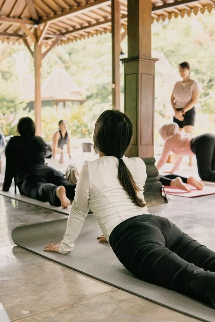 Group of practitioners in a calm outdoor yoga session among trees