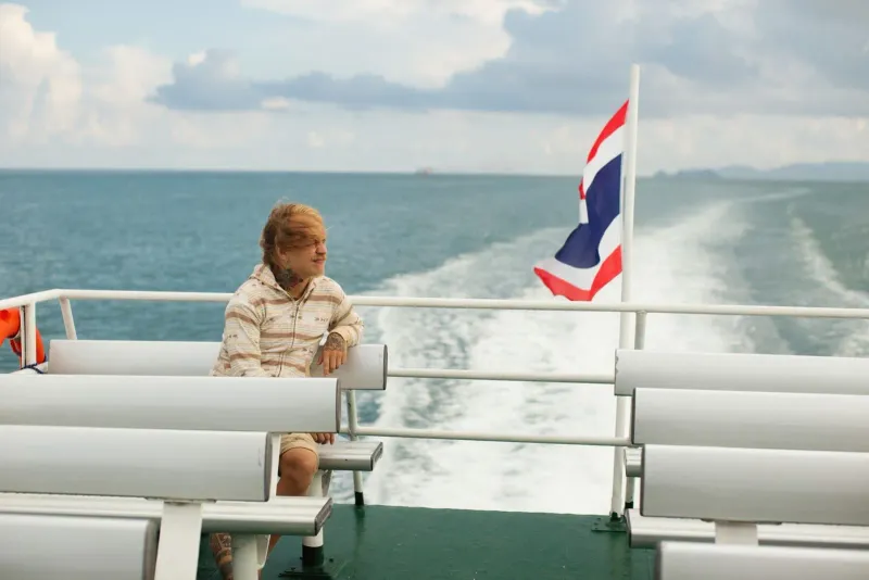 Traveler on a ferry with a Thai flag crossing the Gulf of Thailand between the three islands
