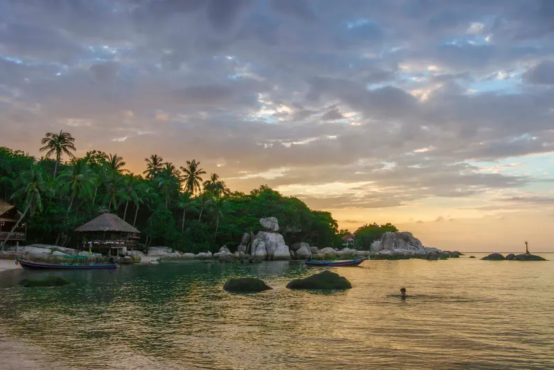 Rocky shoreline and calm water at sunset on a free Koh Samui public beach