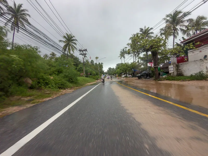Coast road through Hua Thanon near Krua Chao Baan restaurant during a rain shower, southeast Koh Samui