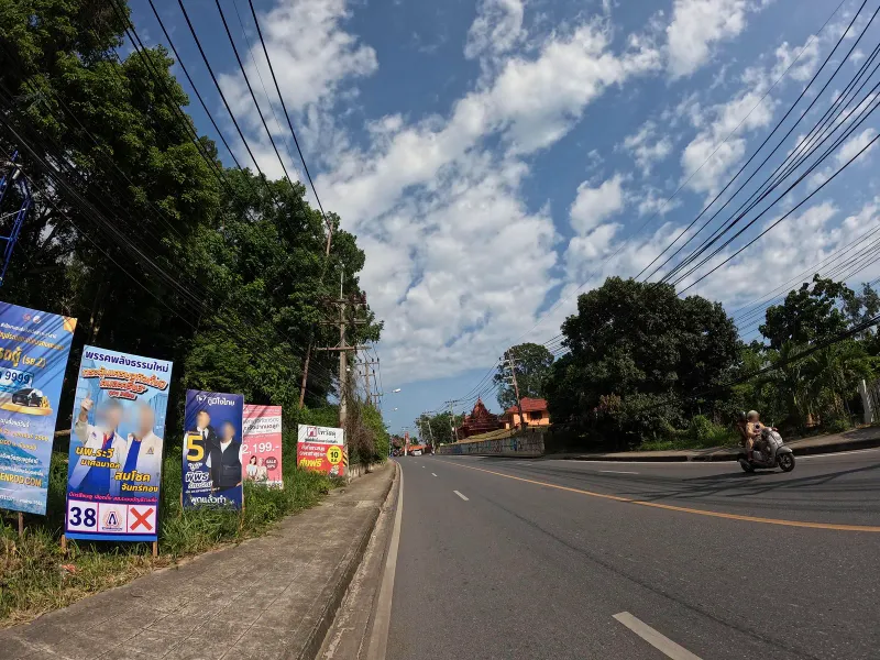 Roadside billboards and coconut palms on the road into Maret village near Krua Chao Baan seafood restaurant