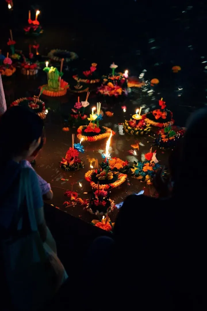 Colorful floating lanterns lighting up the water at night during a Loy Krathong celebration in Thailand