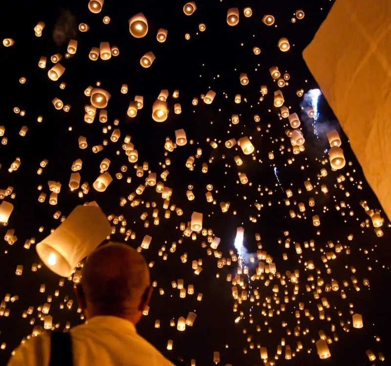 Sky lanterns released into the night sky during Chiang Mai's Yi Peng festival, distinct from Samui's water-based Loy Krathong
