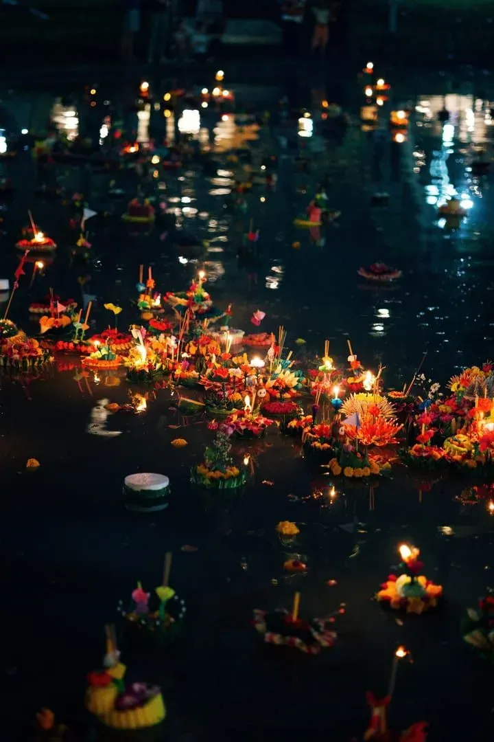 Floating krathongs with lit candles creating a glowing night scene during Thailand's Loy Krathong festival