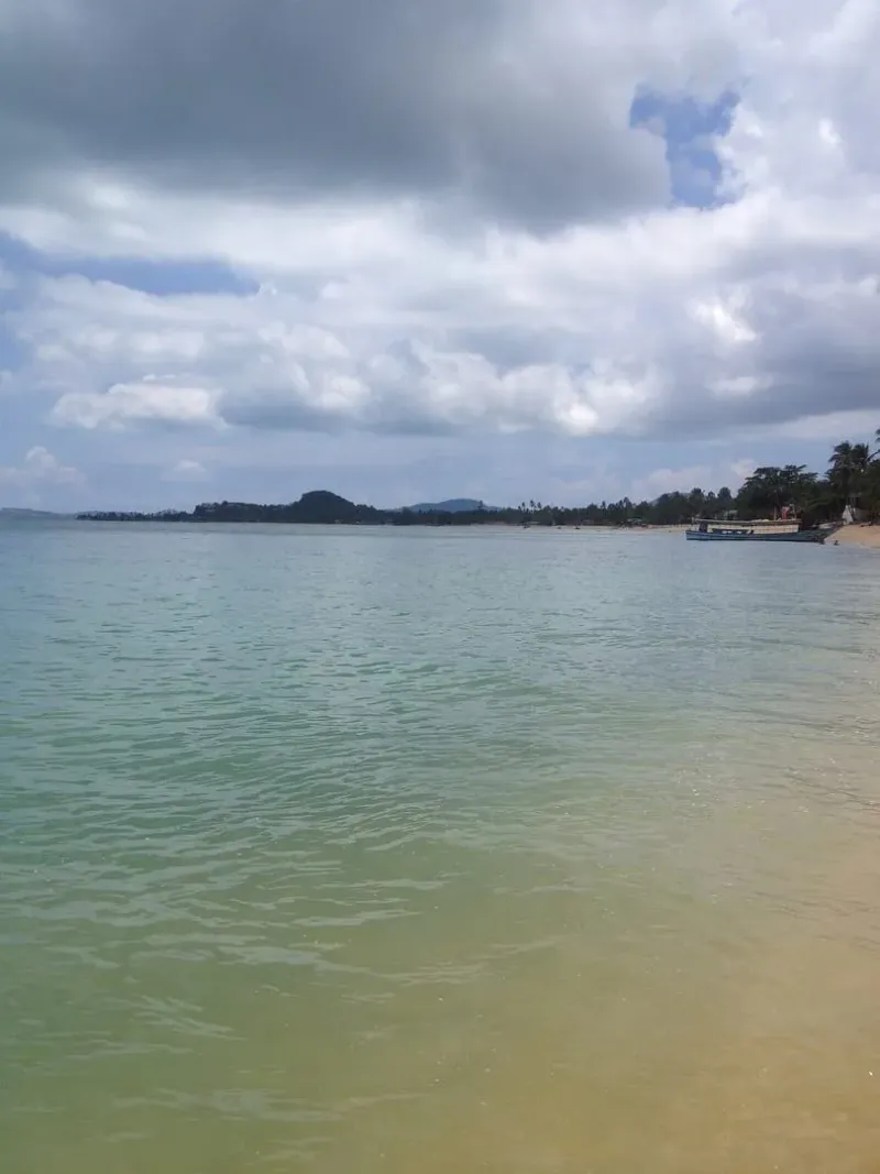 Hazy view across the strait with a moored boat, from Maenam Beach, Koh Samui