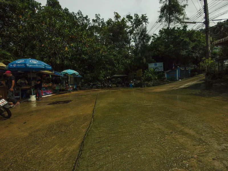 Roadside food stalls and umbrellas near the Hin Lad trailhead entrance