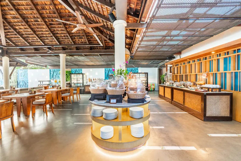 Melati Beach Resortの、ビュッフェカウンターと木の梁の屋根がある開放的なレストラン