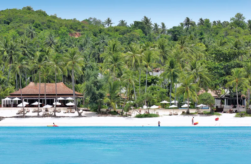Melati Beach Resortのビーチとインフィニティプールの縁。湾の向こうにヤシと山が見えます