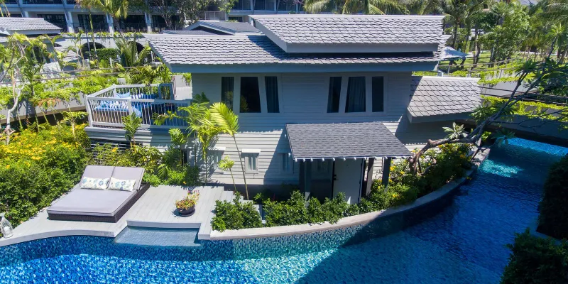 Suite a bordo piscina con solarium di lettini accanto al canale della laguna al Melia Koh Samui vista dall'alto
