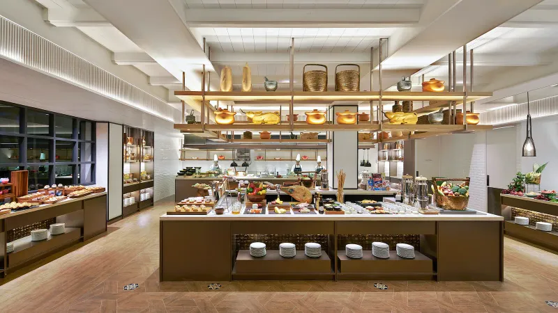 Buffet della colazione al Melia Koh Samui con un'isola centrale di cibi, cucina a vista e chef al lavoro