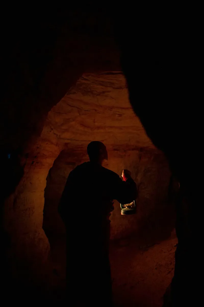 Silhouette eines Mönchs im Lichtstrahl in einer Höhle