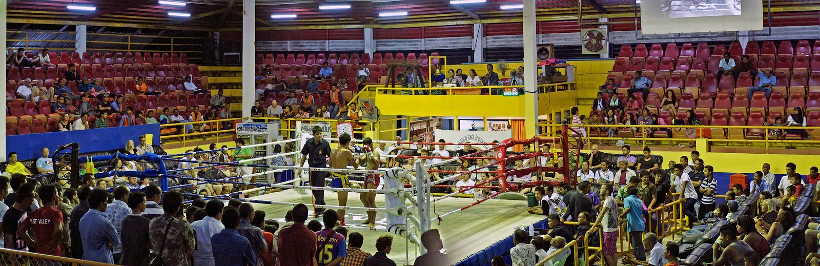 Muay Thai bout in a ring surrounded by spectators in a Thai stadium