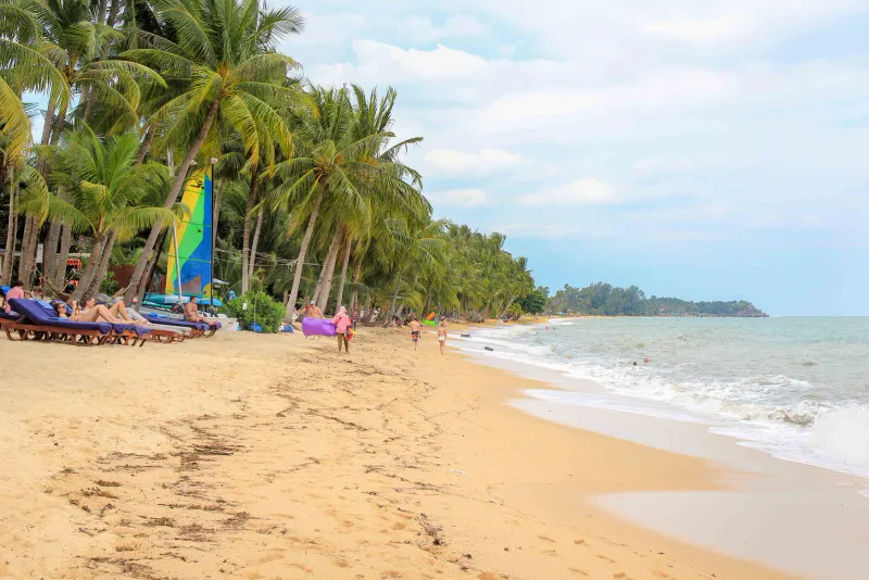 Ein belebterer Strandabschnitt weiter entlang der Küste Koh Samuis, palmengesäumt und sandig