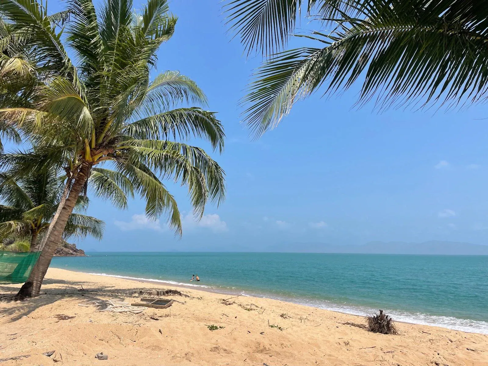 Ruhiger lokaler Strand mit einem Fischernetz, das unter Palmen trocknet