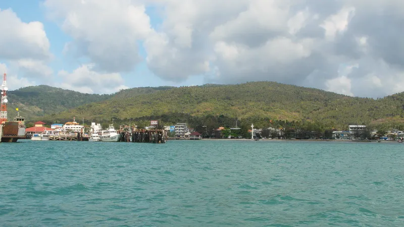 Vue au-dessus de la mer sur l'embarcadère de Nathon et le village au pied de collines boisées à Koh Samui