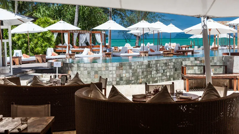 Poolside seating at Nikki Beach Koh Samui's restaurant with daybeds and the sea beyond