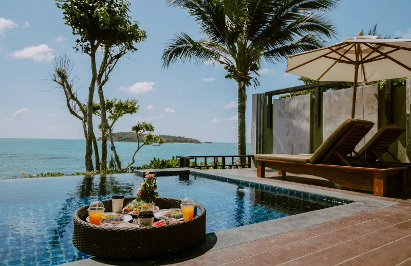 Plateau de petit-déjeuner flottant près d'une piscine à débordement privée face à la mer au Nora Buri Resort